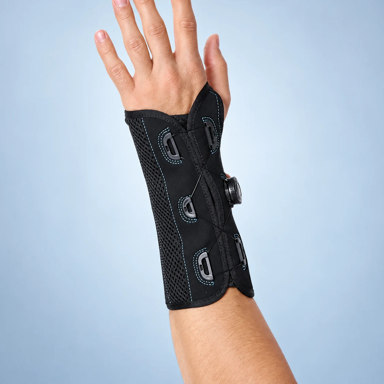 On-body view of the black dial-adjust wrist brace; reference orientation retained